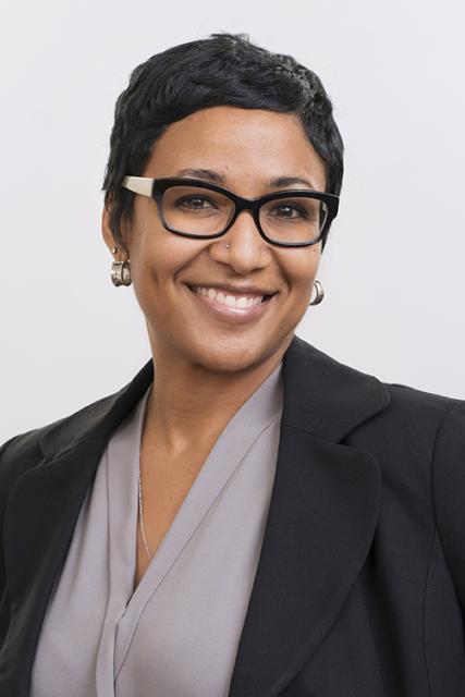 Dr. Amani Allen, a smiling Black woman with short hair, glasses, and earrings