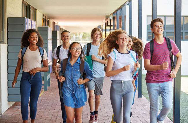 Students smiling and running towards camera thru a school corridor