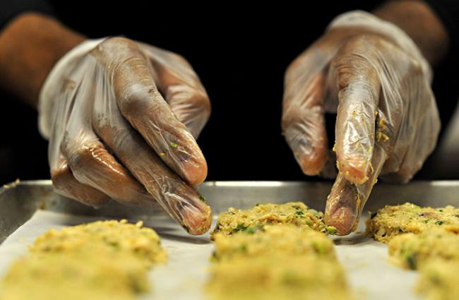 Image of a person in gloves preparing food.