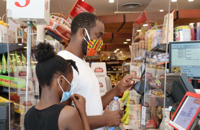 Black man and girl wearing face masks purchasing items at store during coronavirus pandemic