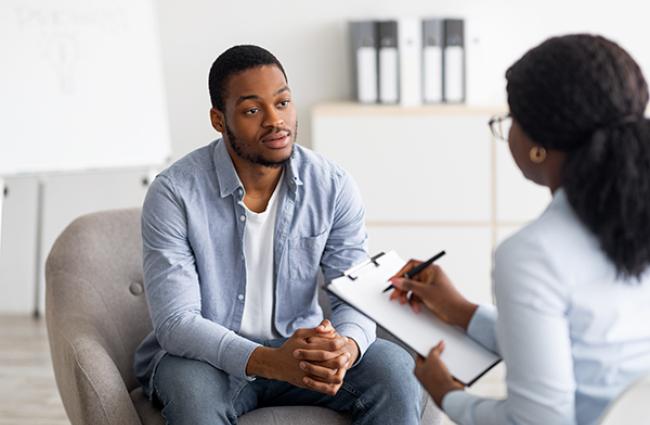 Serious looking young Black man being interviewed by a young Black woman in an office setting