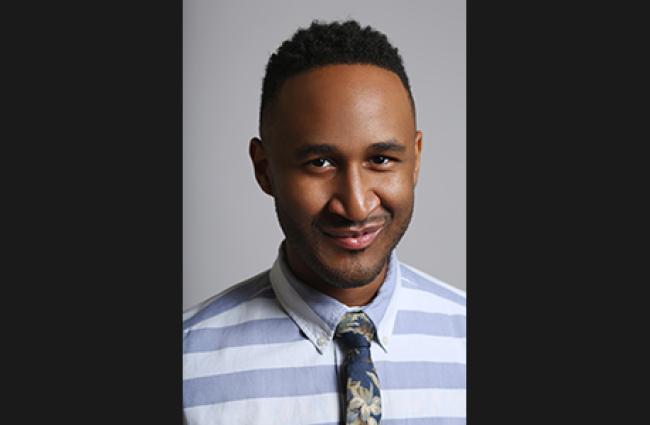 Terrell Winder, a smiling Black man wearing a blue and white stripped collared shirt and floral tie