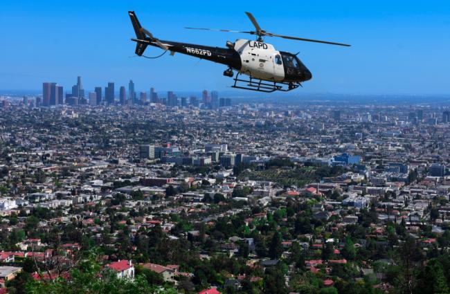 LAPD helicopter flying over residential area with LA skyline in the background