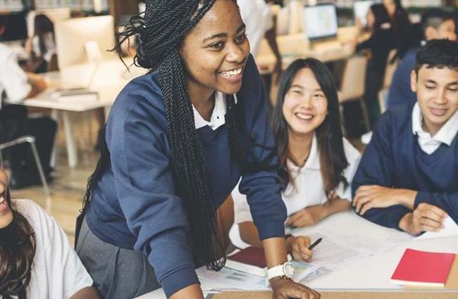 Group of diverse young people sitting at a desk with paper and collaborating