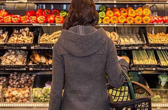 Woman stands in front of a colorful array of fresh produce