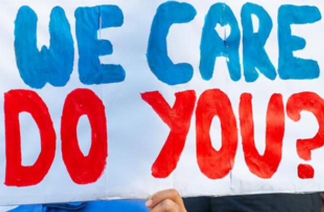 Person holding up a sign that reads "We Care Do You?