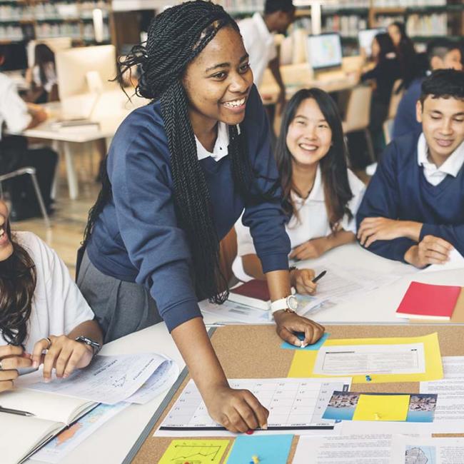 Group of young students at large table discussing a project