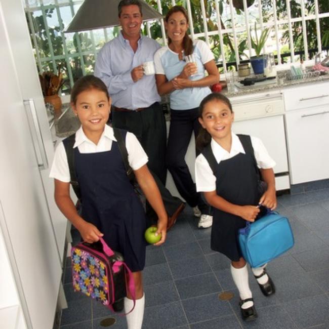 Children in school uniforms ready for school standing in front of parents