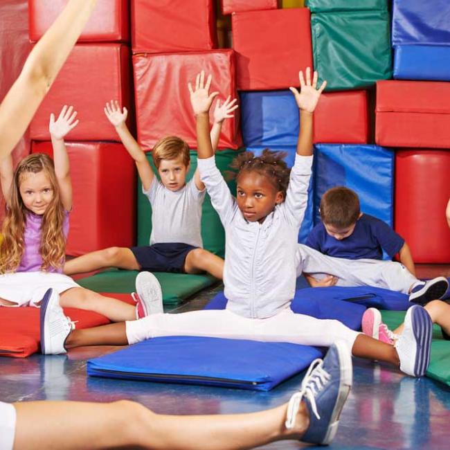 Children in PE class stretching their arms into the air