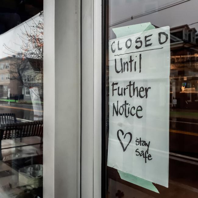 Storefront window with "Closed until further notice" sign in window due to COVID