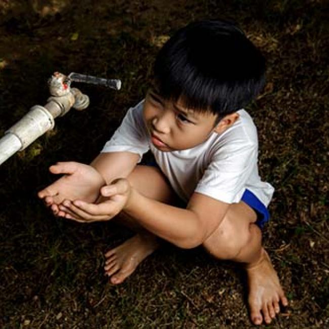child drinking water with hands
