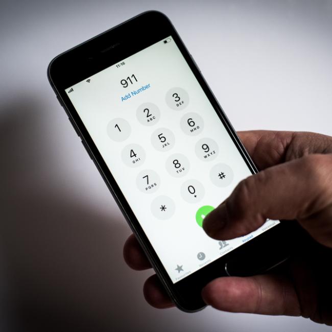 Black hand holding a phone dialing 911