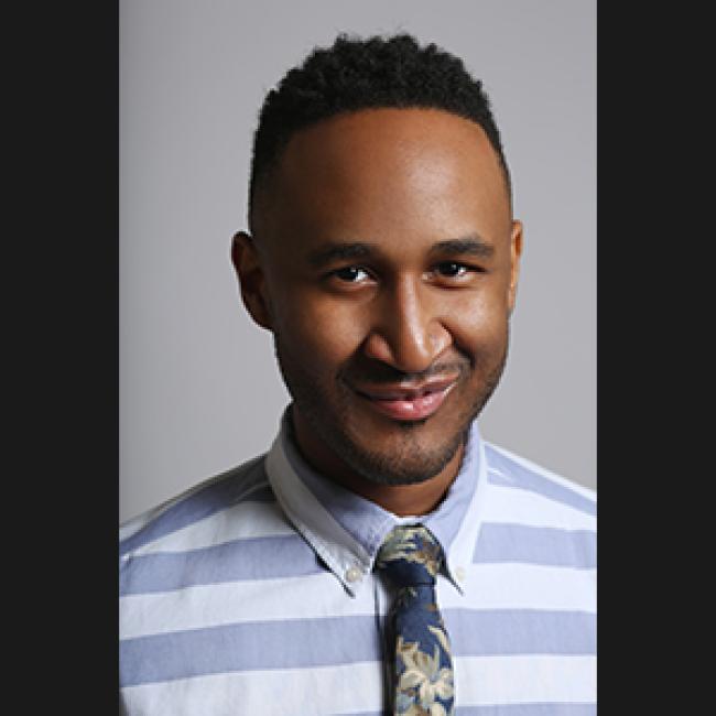 Terrell Winder, a smiling Black man wearing a blue and white stripped collared shirt and floral tie