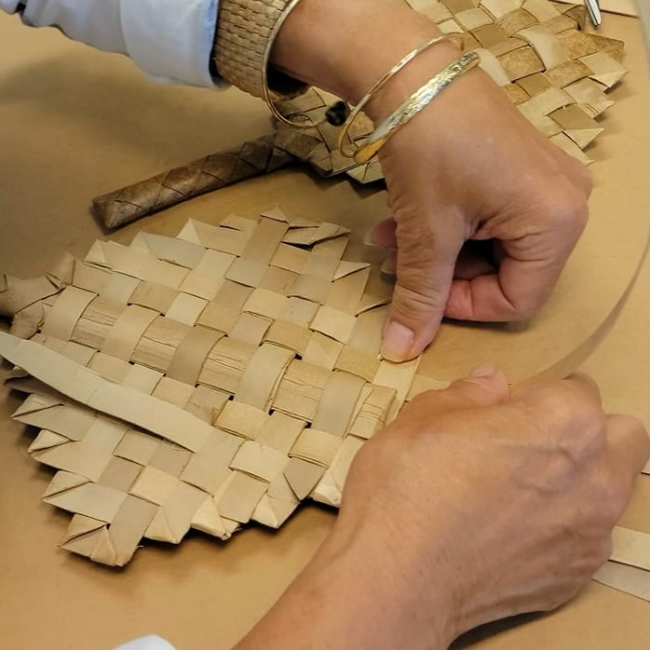 This image is of a lauhala fan being woven together by a woman. Lauhala is the leaf of the pandanus tree that is picked when dried, prepped, and woven together to make various things including mats, fans, ornaments, sails, etc. The team believes the interlocking of the leaves is similar to what we hope for with our project of weaving together Indigenous and western perinatal care in Hawaiʻi.