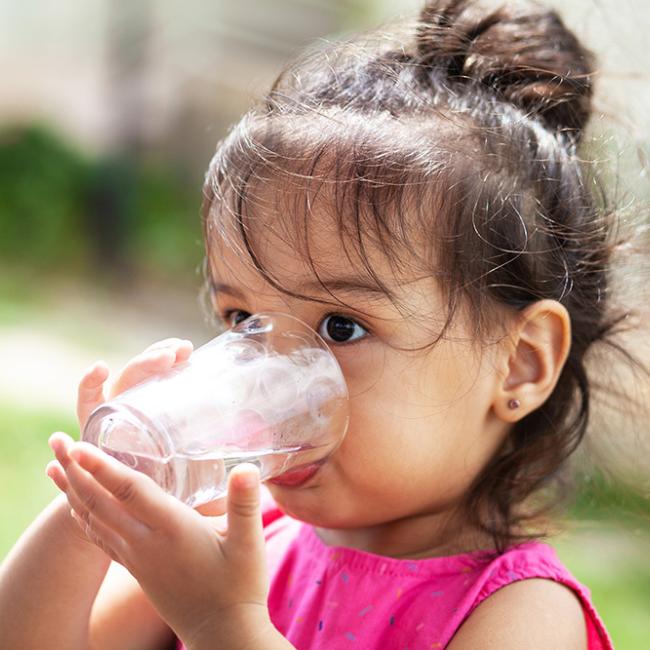 Little girl wearing a pink shirt drinking water