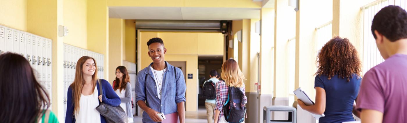 Adolescents walking down a bright school hallway