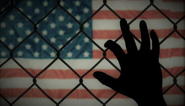 Hand silhouette on chain link fence with American flag in background