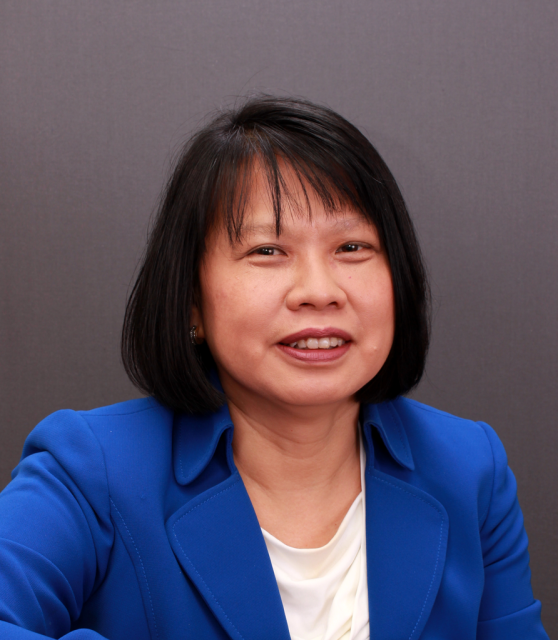 Cam Escoffery, smiling woman with shoulder length black hair and bangs wearing a blue blazer over a white shirt