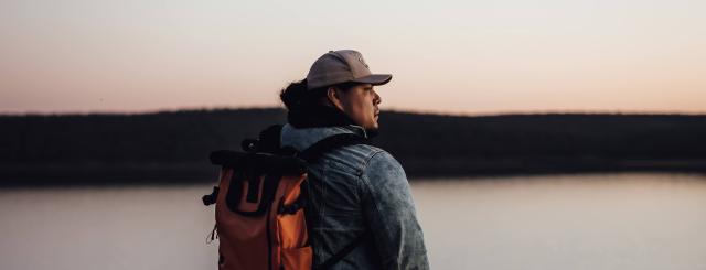 Cody Hammer, an Osage man, standing in front of a body of water and looking at the horizon 